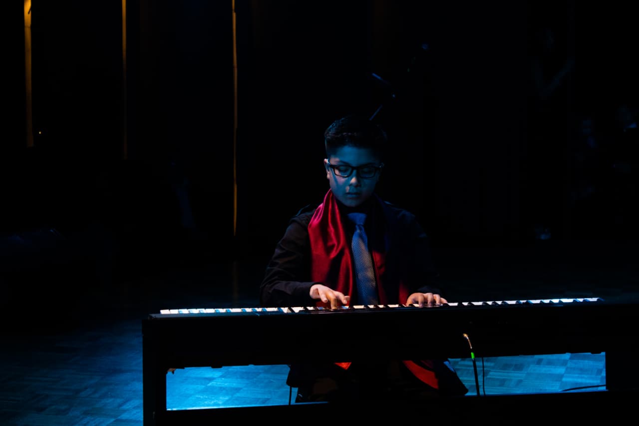 Estudiante interpretando piano bajo una luz azul